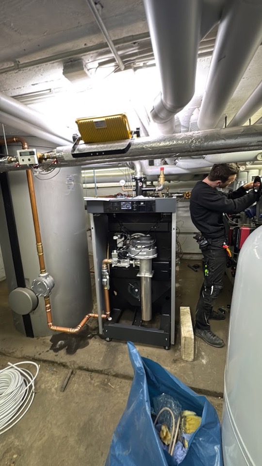 Monteur bei Arbeit an Heizungskessel und hydraulischer Anbindung